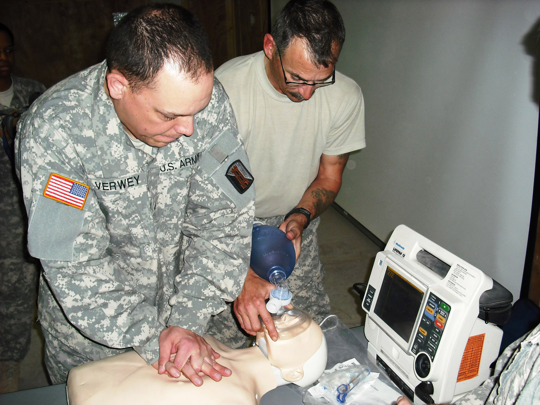 Medical personnel perform CPR on a simulated cardiac arrest patient during an ACLS practical examination.