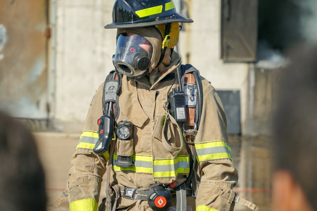 Firefighter in full turnout gear and SCBA facepiece working at a structure fire.