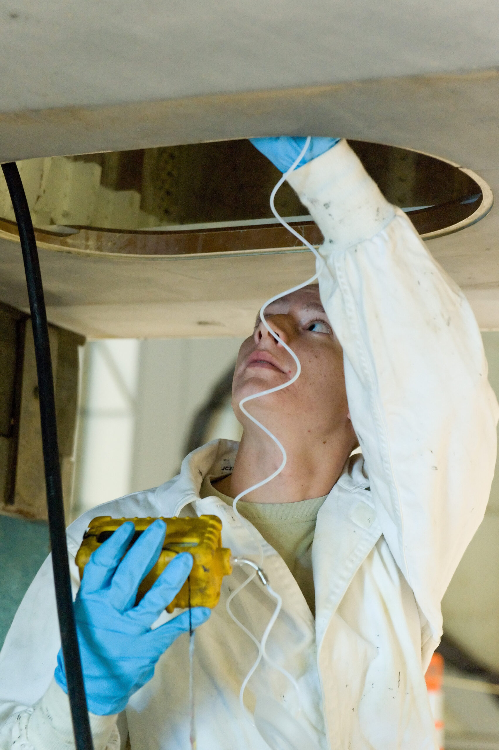 Worker using a direct-reading instrument to sample the atmosphere at a confined-space access point during training