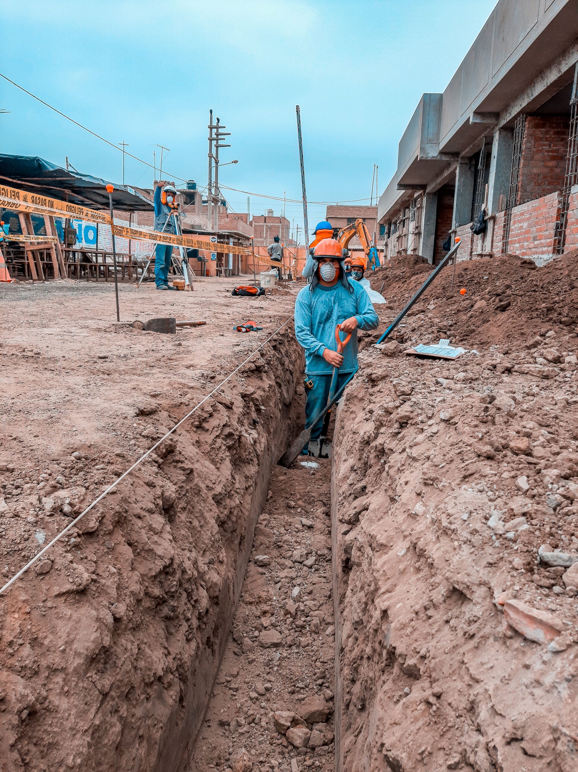 Construction workers in protective equipment working inside an excavation trench