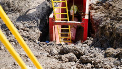 Worker inside a protected trench with ladder access and egress.